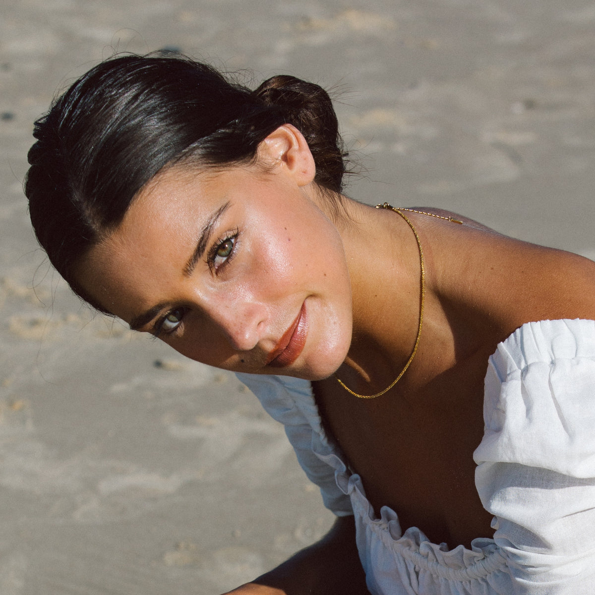 Woman on the beach wearing the Piana gold necklace